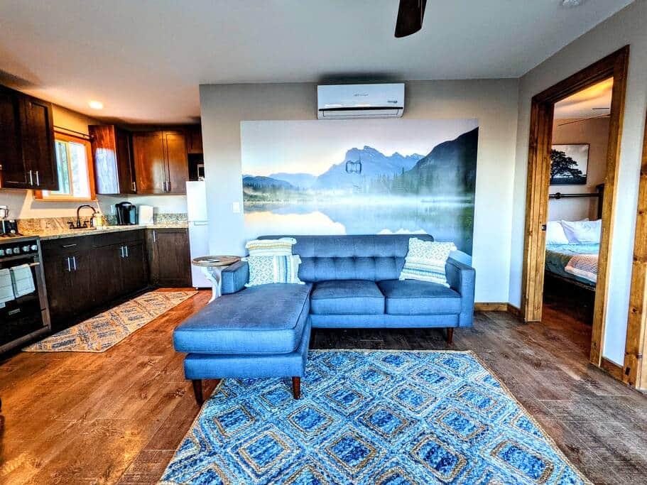 Cozy cabin interior with mountain mural, modern kitchen, and stylish lounge seating